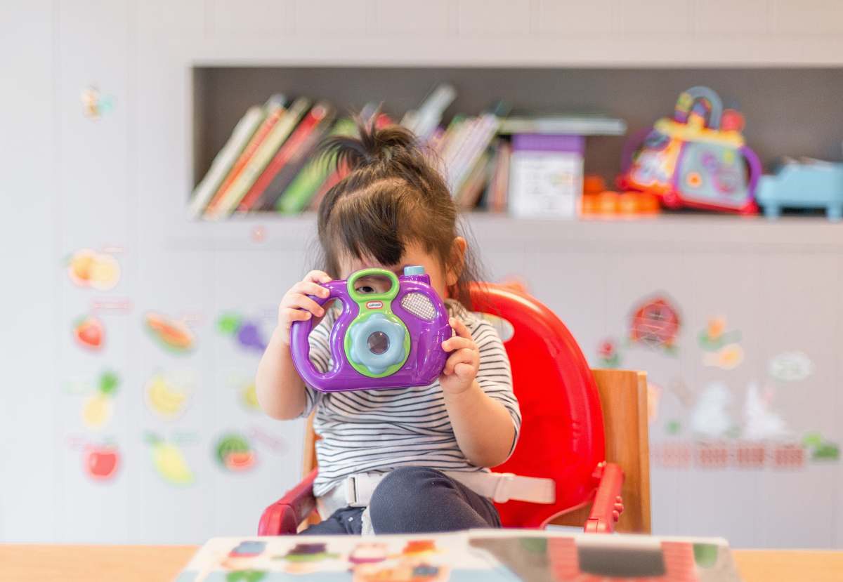 people girl holding purple and green camera toy human