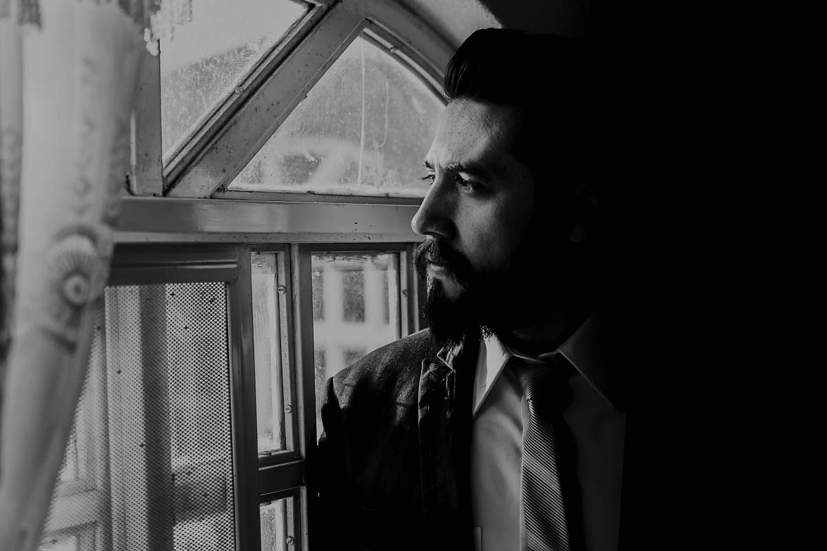 people man in black suit looking out from window person