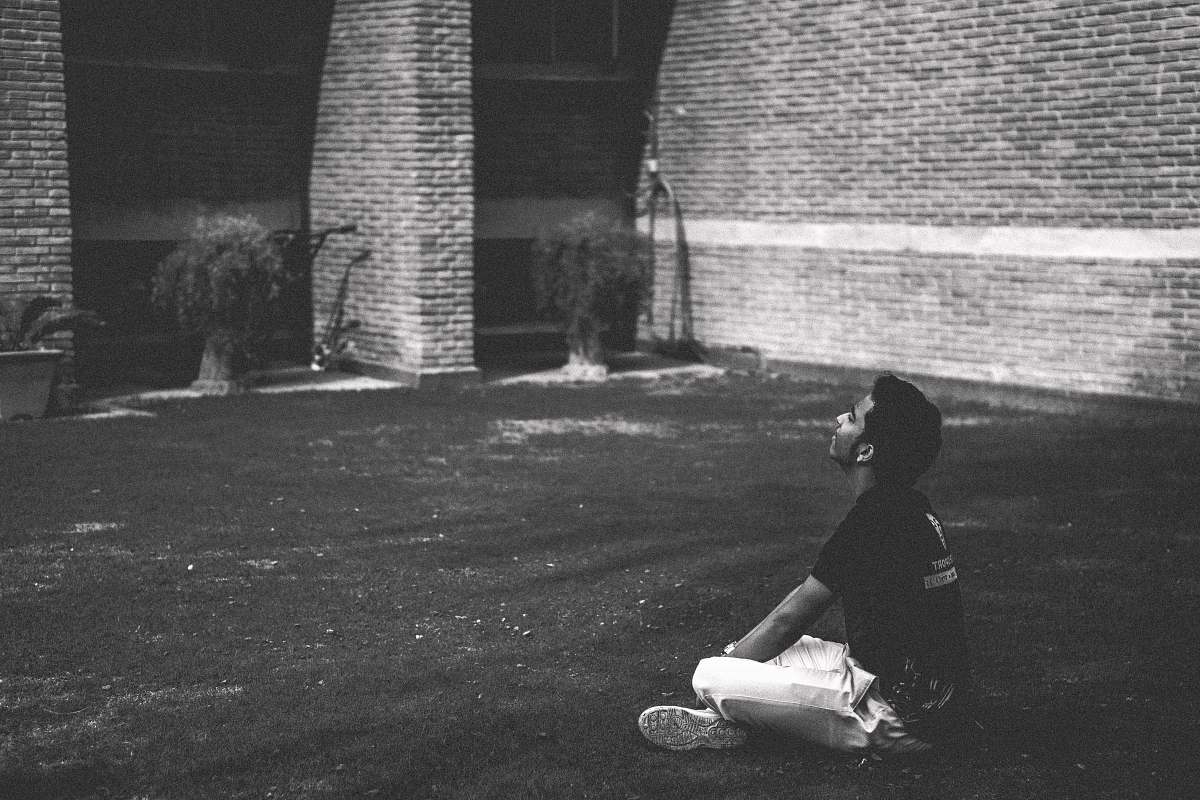 grey man in black t-shirt sitting on grass brick