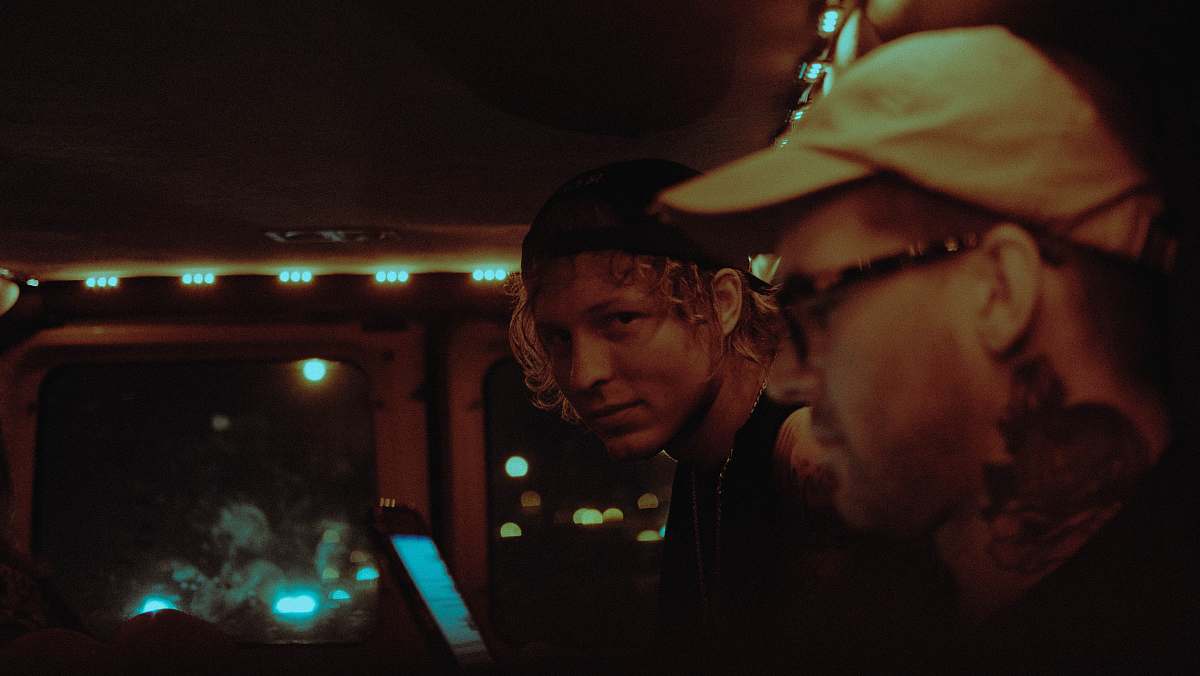 people man wearing cap beside man at nighttime person