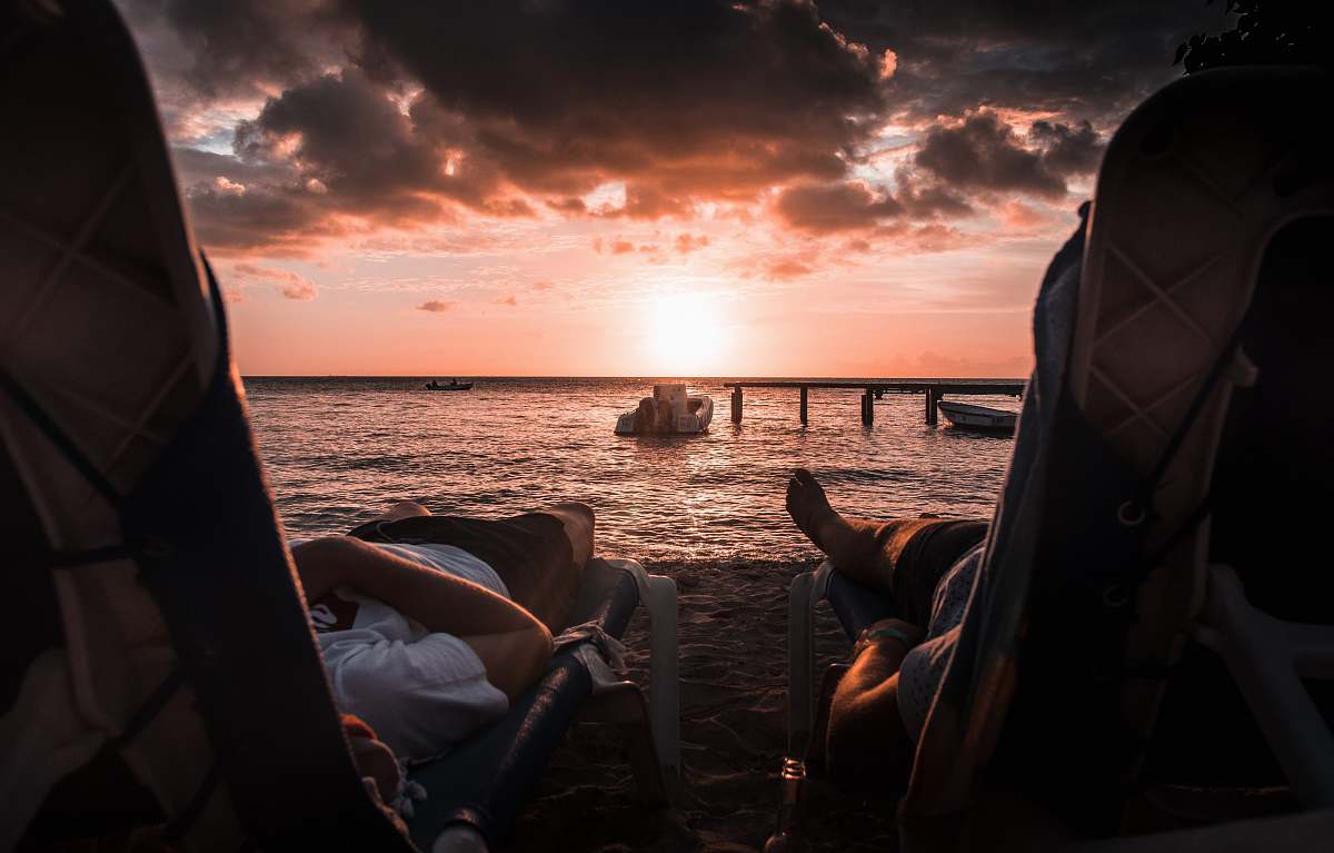 people two person lying on chaise lounge under sunset person
