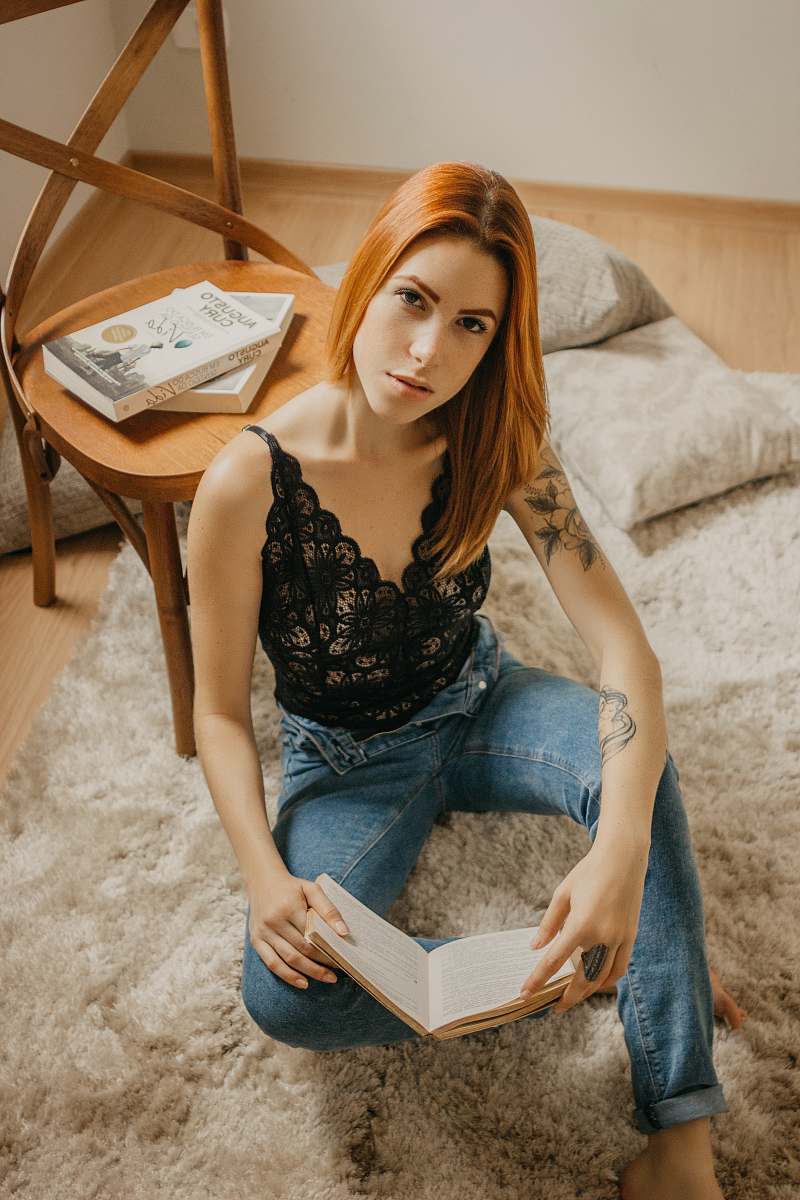 people woman holding book leaning on wooden chair person