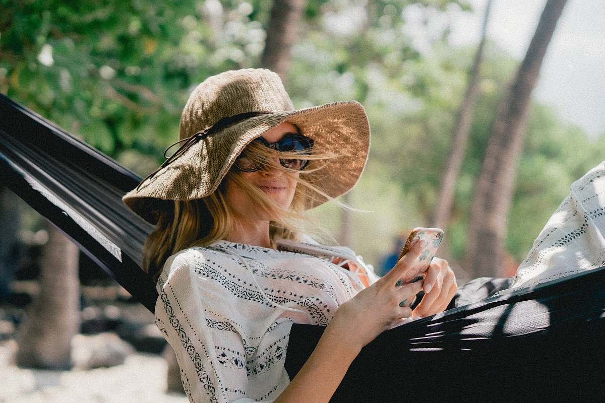 people woman lying on black hammock while holding phone person