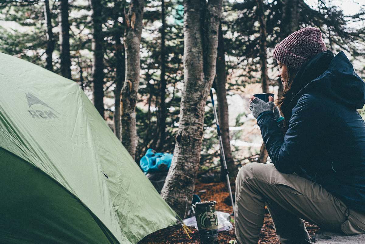 people woman sitting and holding cup of coffee camping