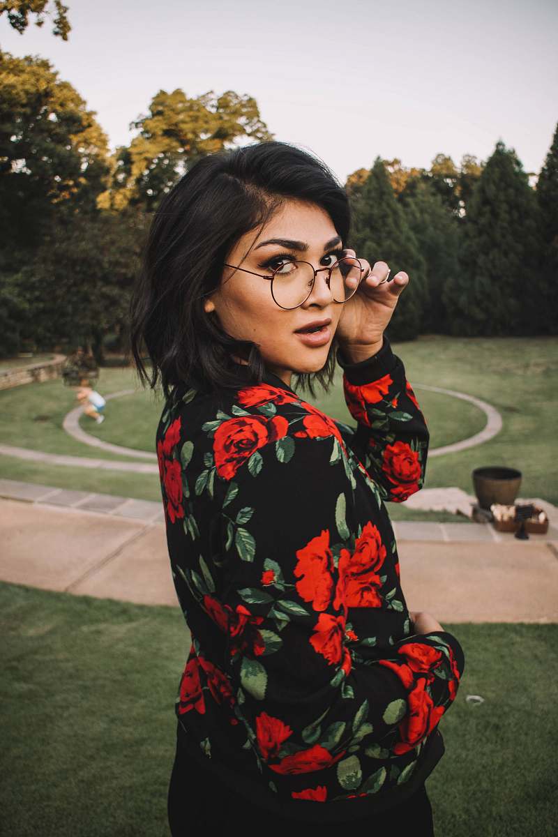 people woman wearing black, green, and red floral long-sleeved top standing on park person