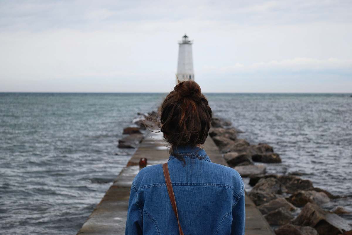 sea woman standing infront of lighthouse near beach water