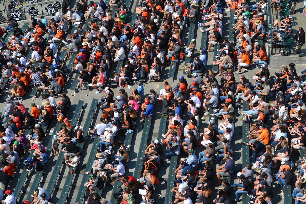 human aerial photography of people sitting on benches during daytime crowd