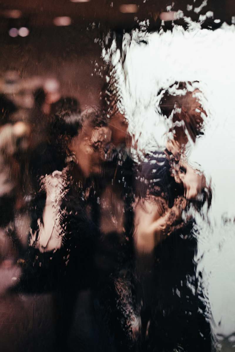 human blurry reflection of light of two persons on glass window person