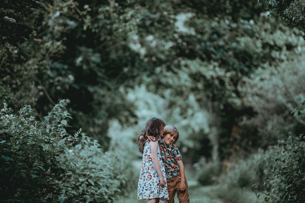 person boy and girl standing in middle of forest trail human