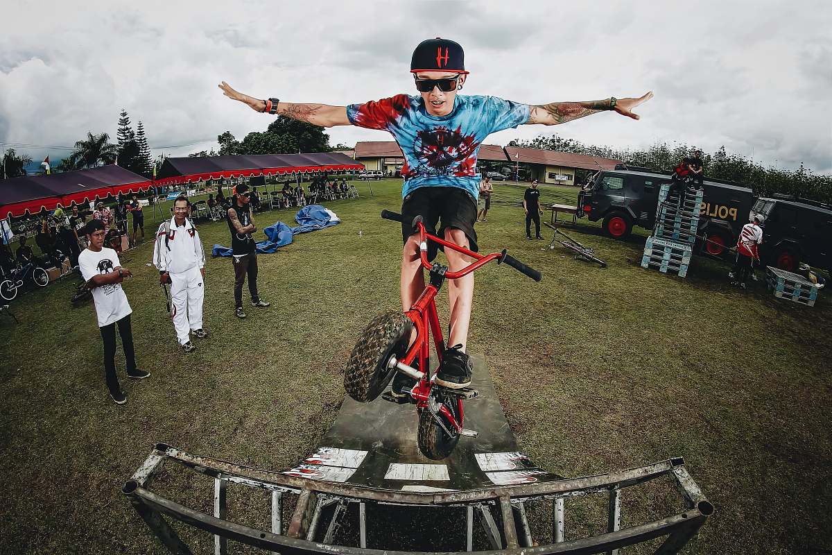 human boy doing bicycle tricks in front of many people person