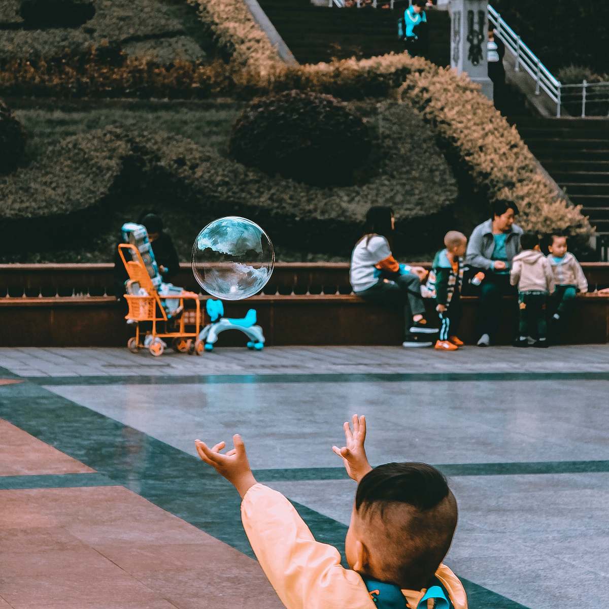 person boy reaching bubble near sitting woman during daytime bubble