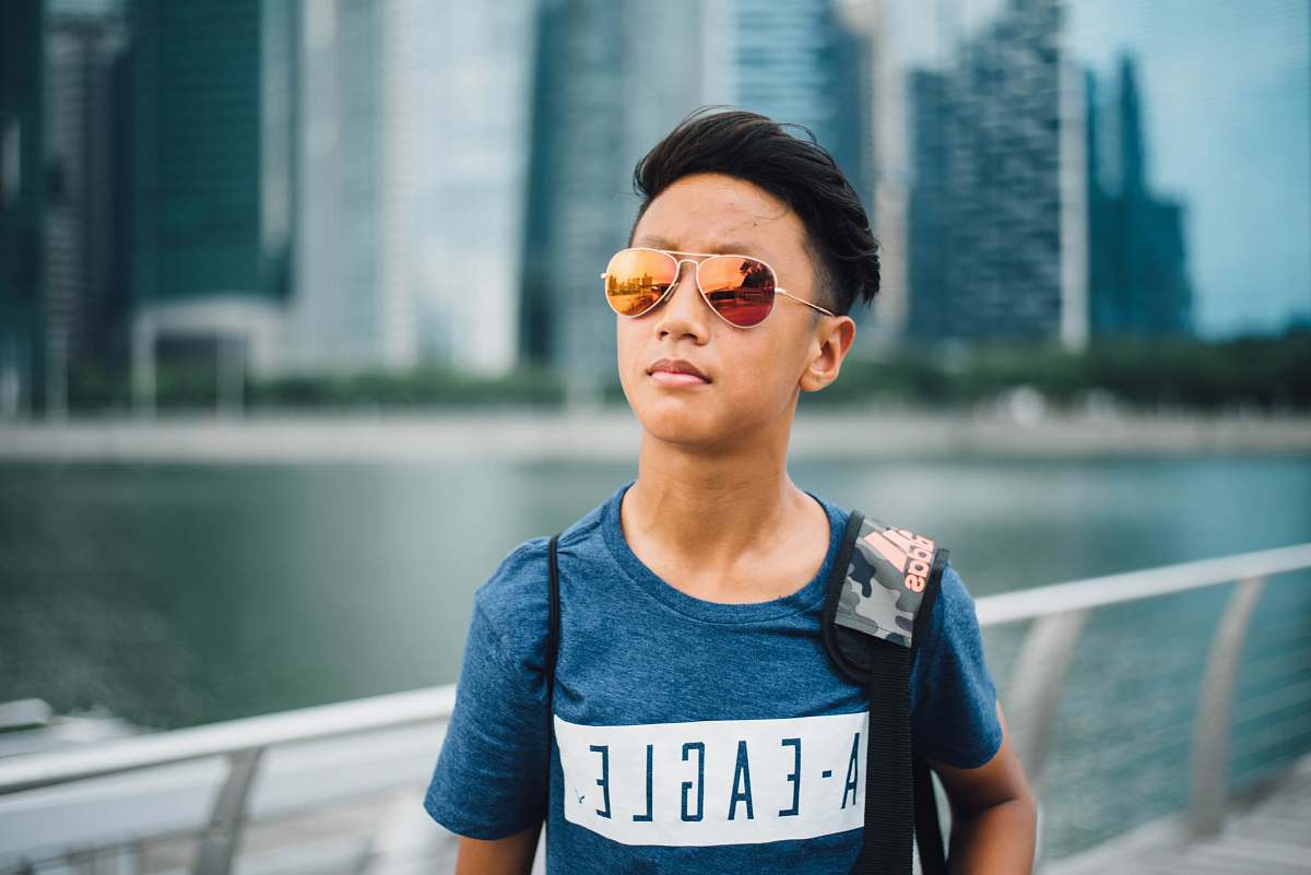person boy wearing yellow lens Aviator sunglasses near gray rail at daytime human
