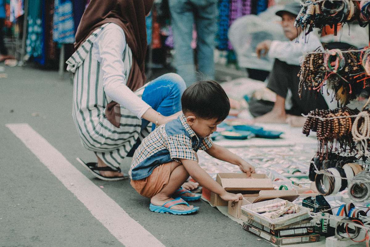 human child doing asian squat on asphalt road person