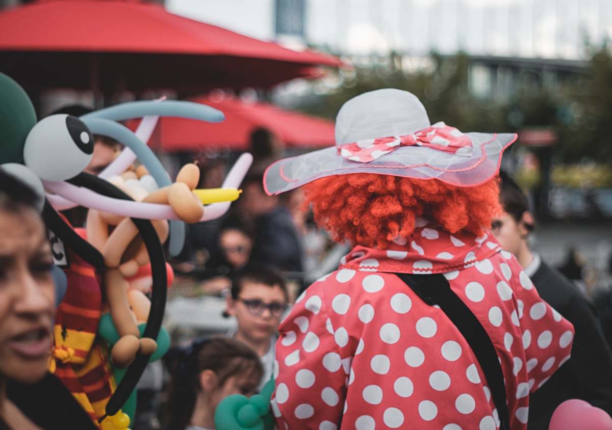 human clow wearing white sun hat surrounded with people during daytime person