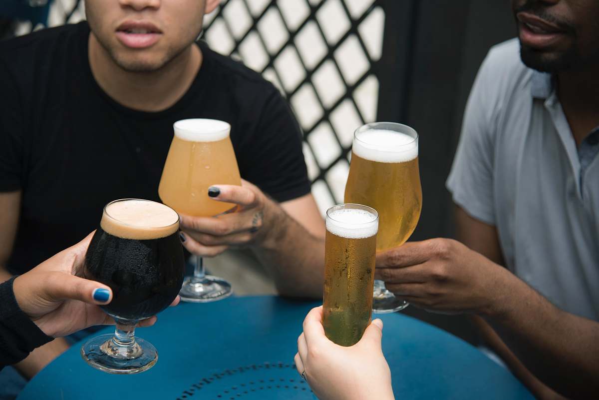 human four person holding glass goblets beer
