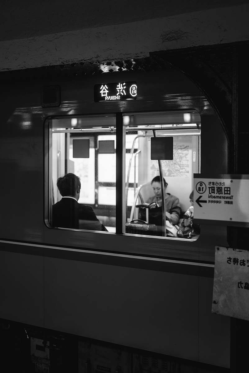 human grayscale photo of two people sitting in train black-and-white