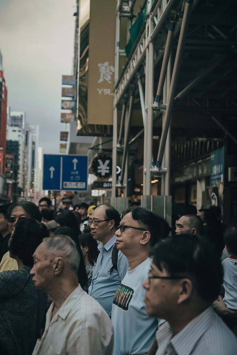 human group of men standing beside building under gray sky person