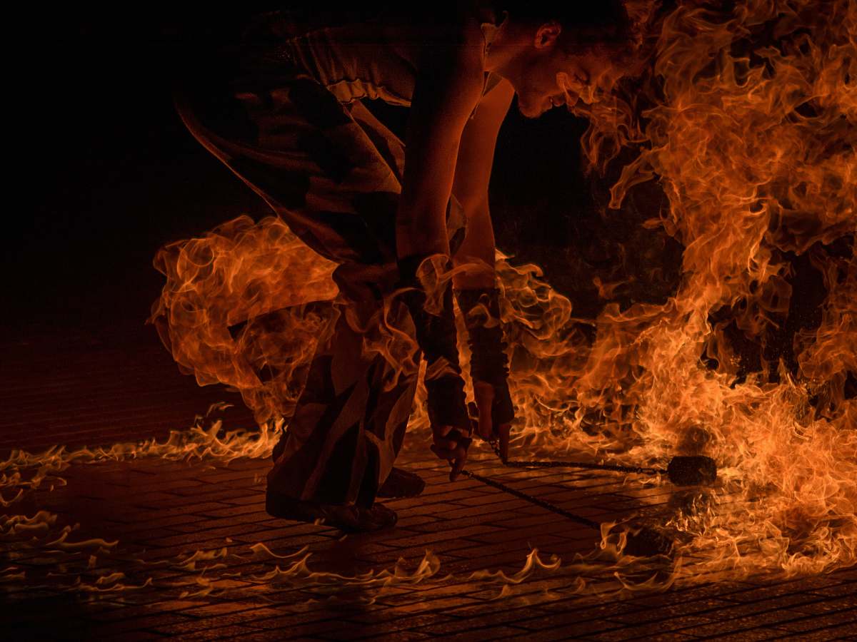 person male fire dancer holding two torches surrounded by fire human