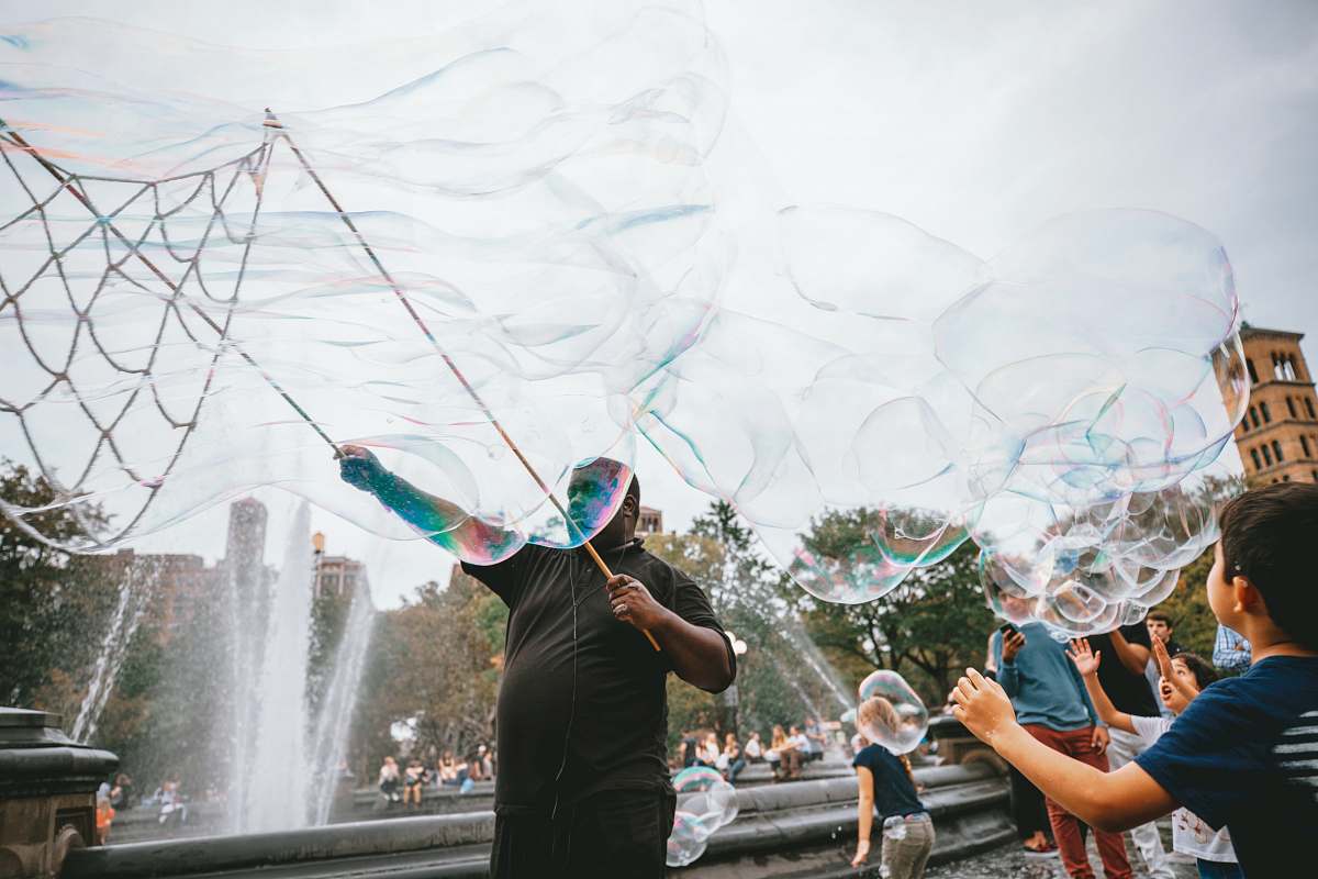 human man and boy performing bubble artworks near fountain at daytime bubble
