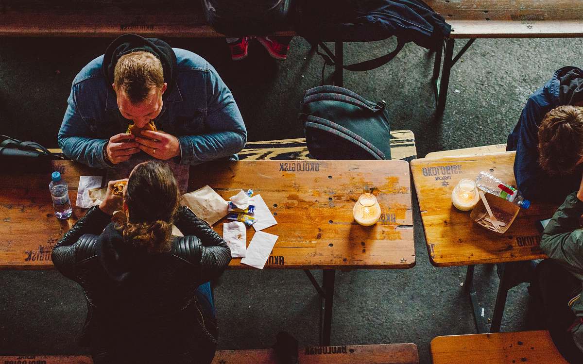 human man and woman eating sandwich infront of table person