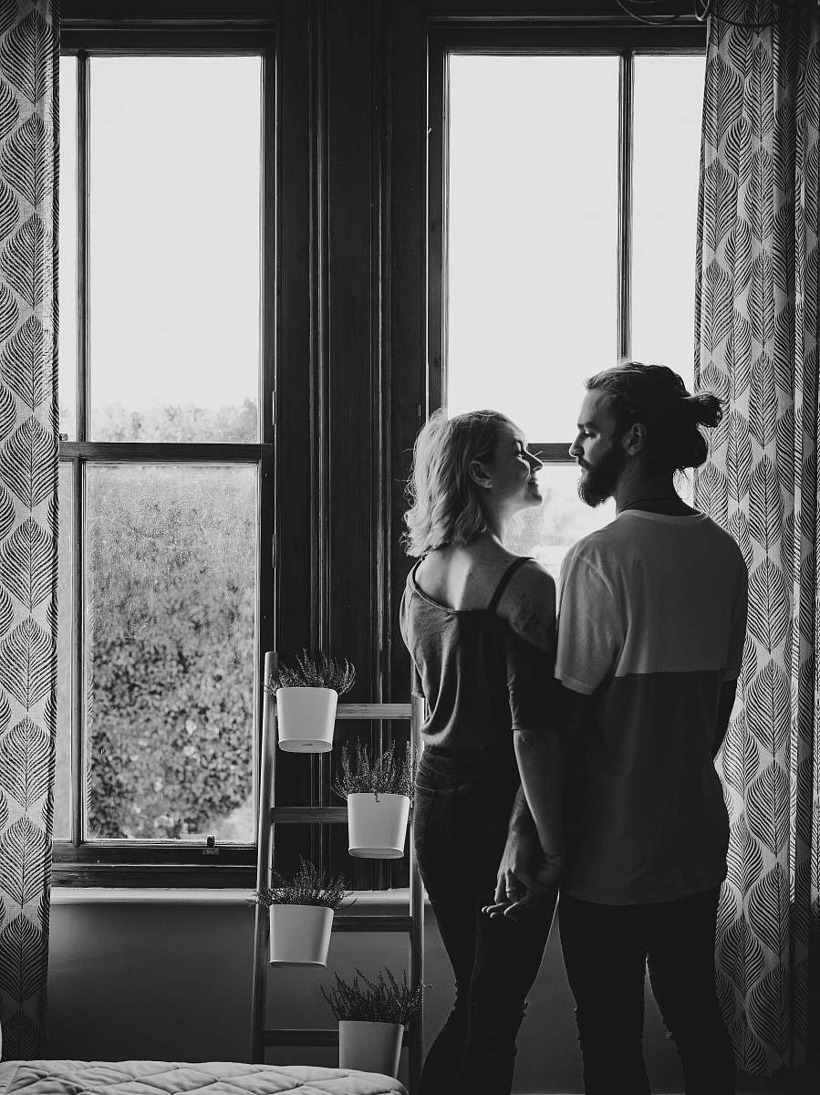 black-and-white man and woman facing each other near window plant