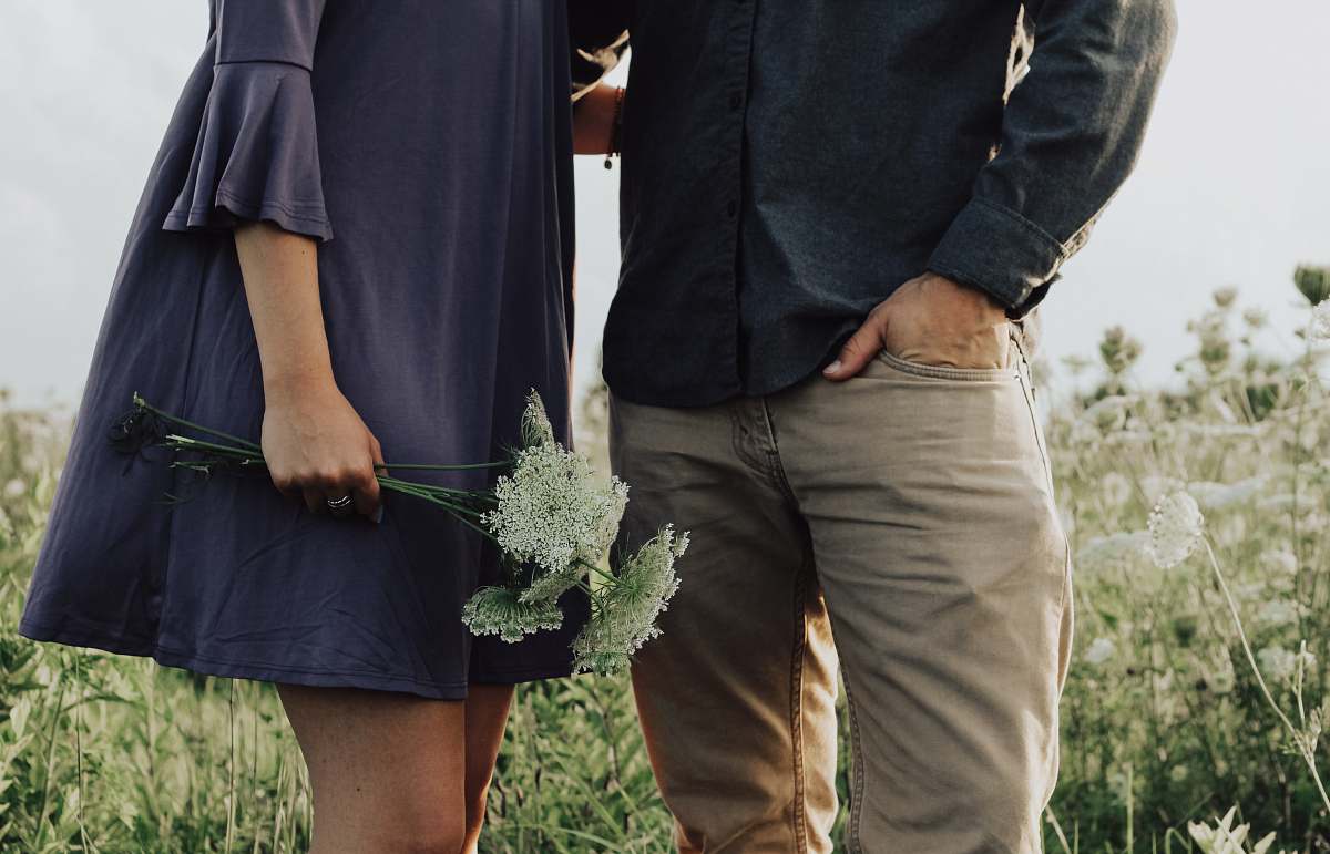 human man and woman standing on white flower field at daytime person