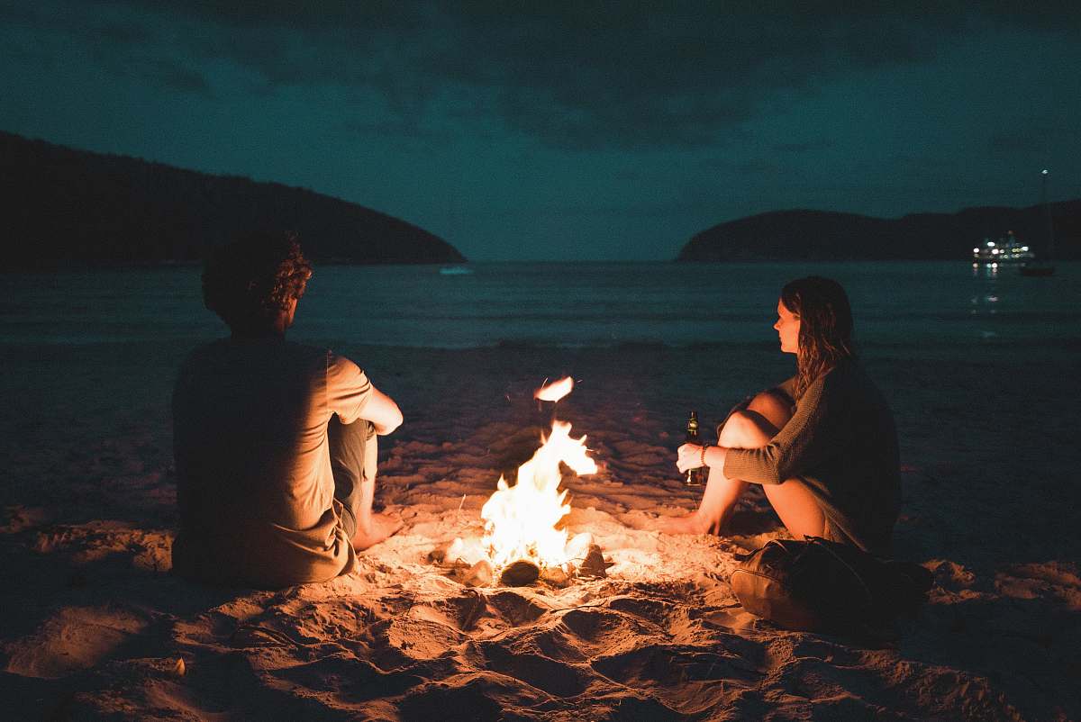 fire man and woman with bone fire sitting on seashore bonfire