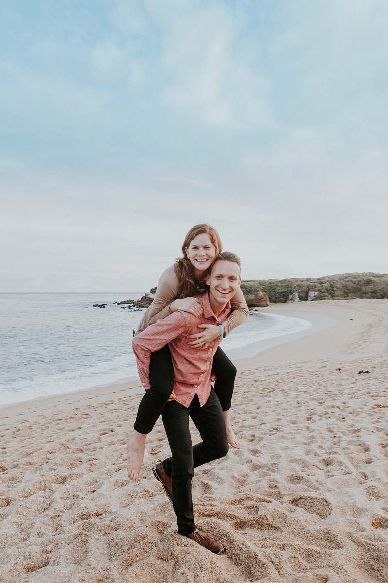 human man carrying woman beside seashore person