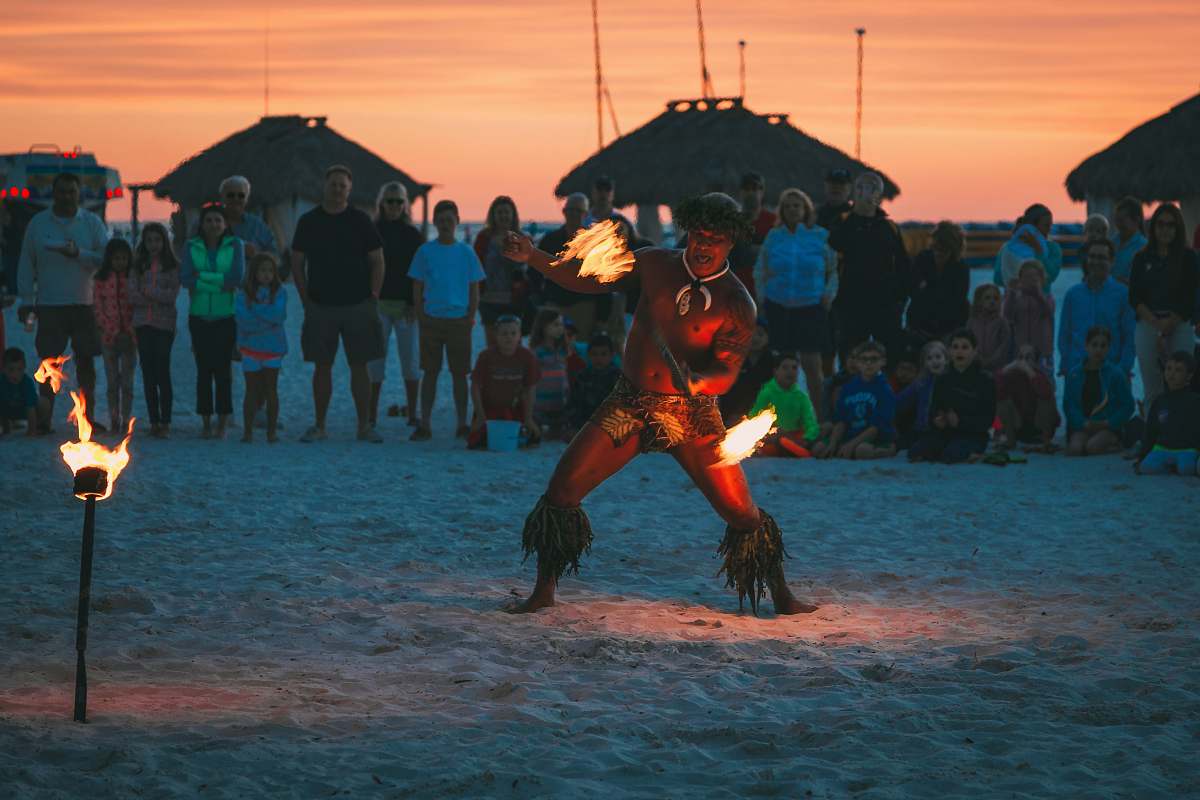 human man dancing fire dance surrounded by people at beach person