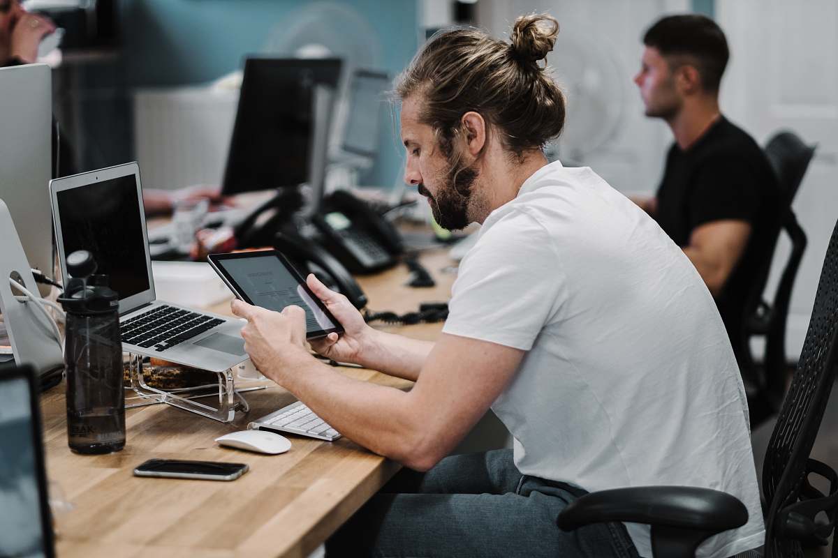 person man holding turned-on iPad in front of turned-off MacBook Air human