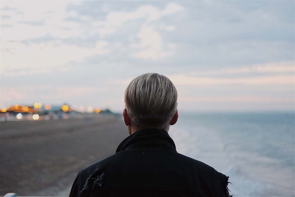 human man in black coat walking on seashore person