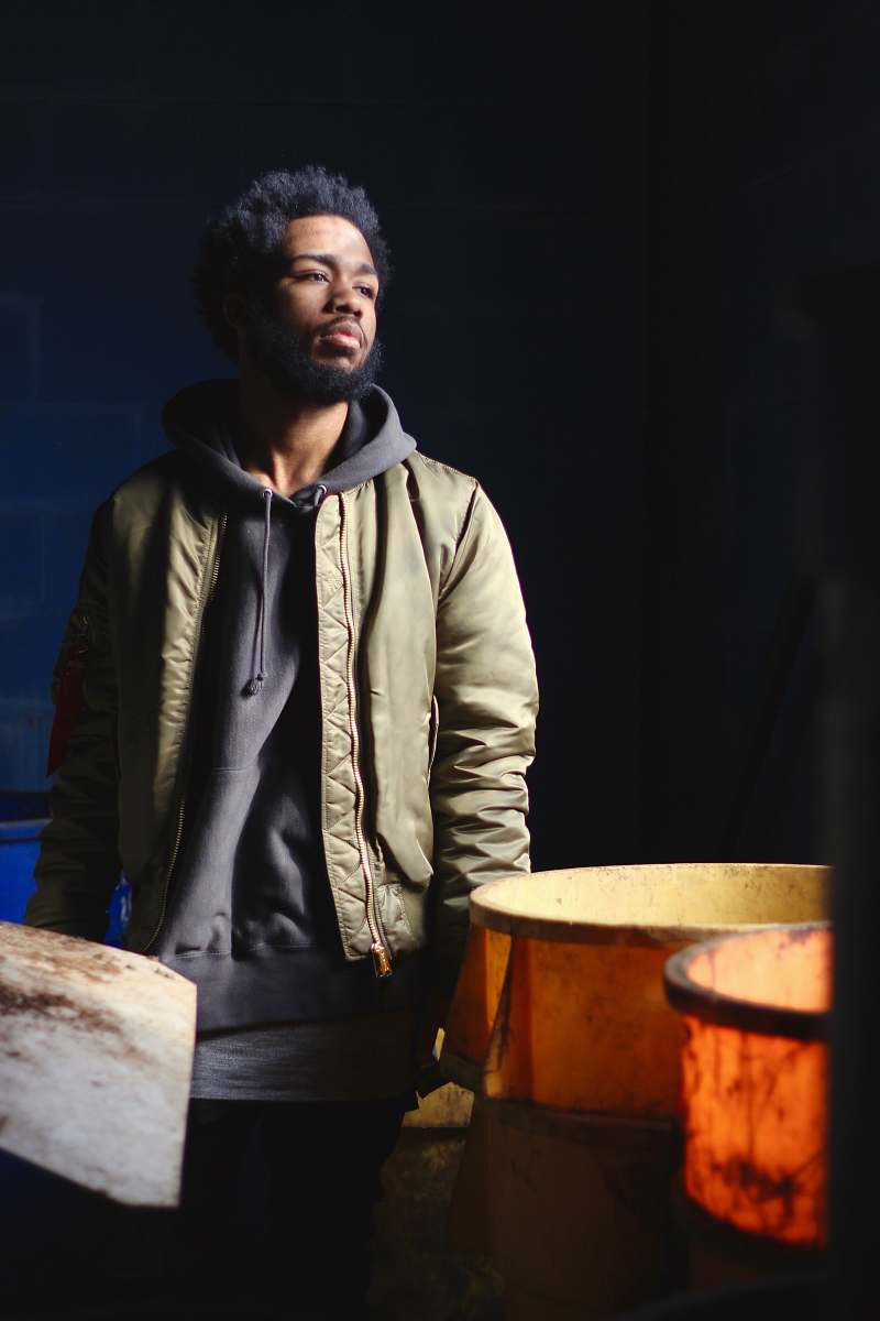 person man in green and black jacket standing near containers human