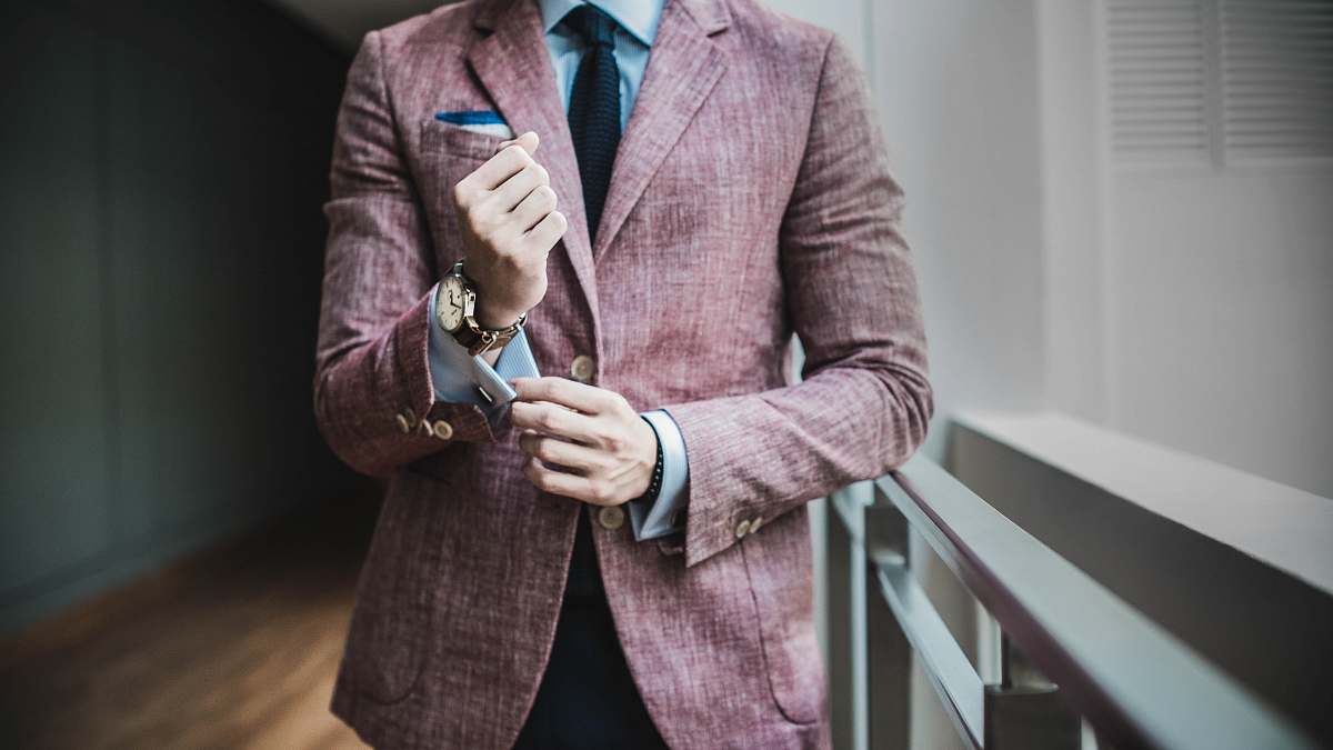 human man in maroon suit jacket beside window with railings person