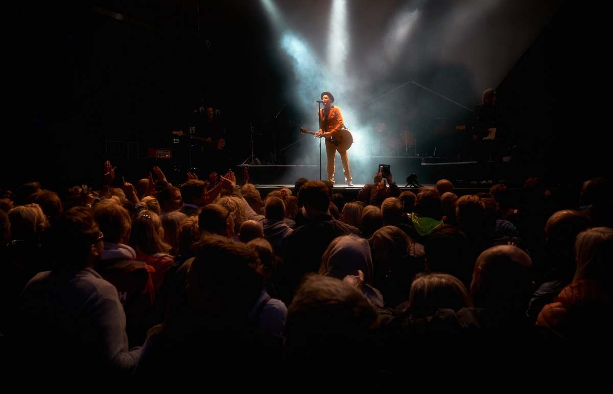 person man playing guitar while performing on stage crowd