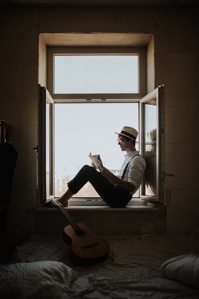human man sitting on window while reading person