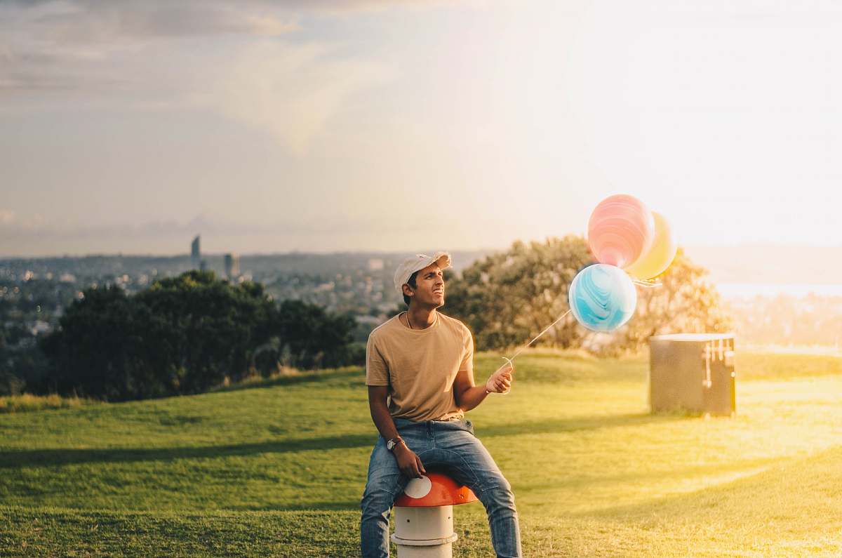 human man sitting while holding balloons person
