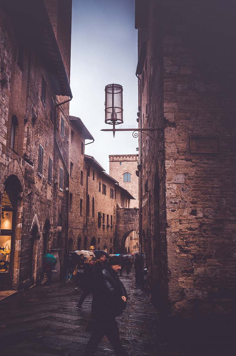 person man wearing black jacket walking on alley building