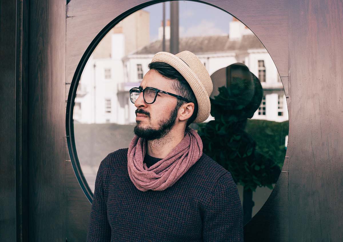 person man wearing eyeglasses and black shirt leaning on glass door while looking up human