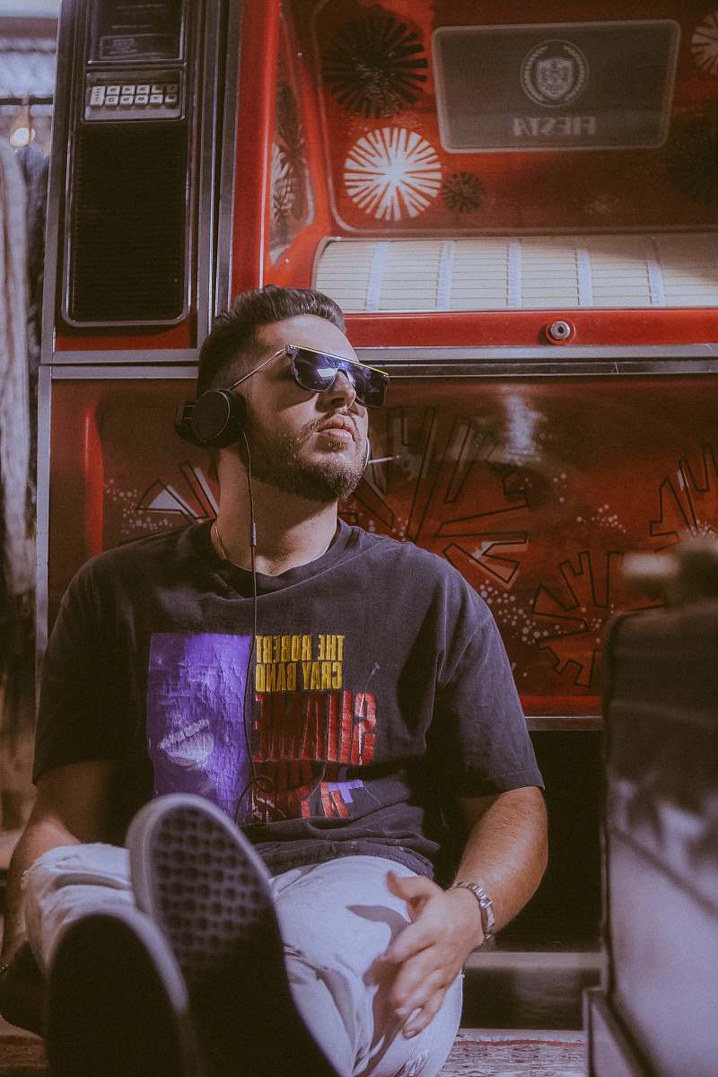 human man wears black t-shirt and black headphones while sitting down person