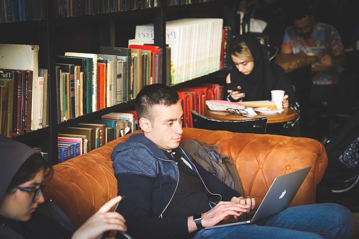 person people sitting beside black wooden book case human