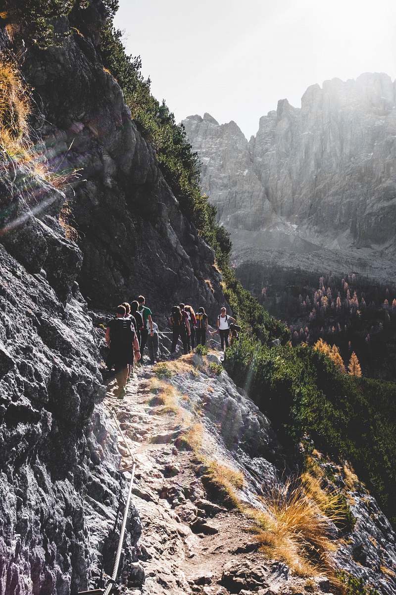 person people walking on mountain road near trees mountain