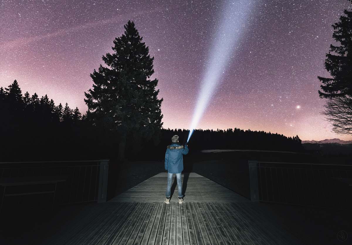 human person holding flashlight aiming on sky person