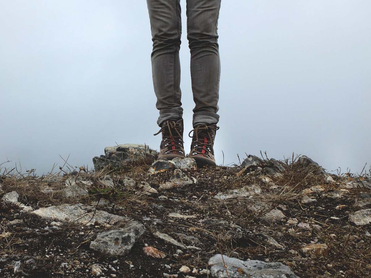 human person in gray jeans standing on rocks during daytime person