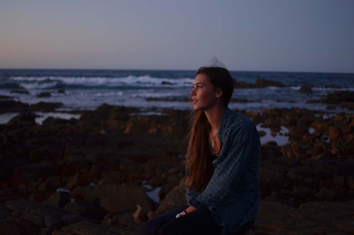 person photo of woman sitting on rocks near beach human