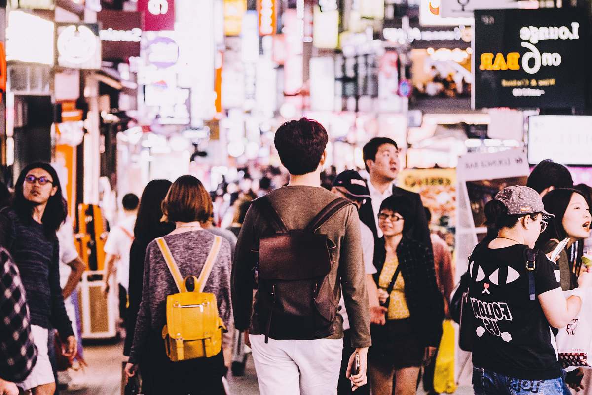 human photography of man wearing brown backpack near lounge on 6 bar person