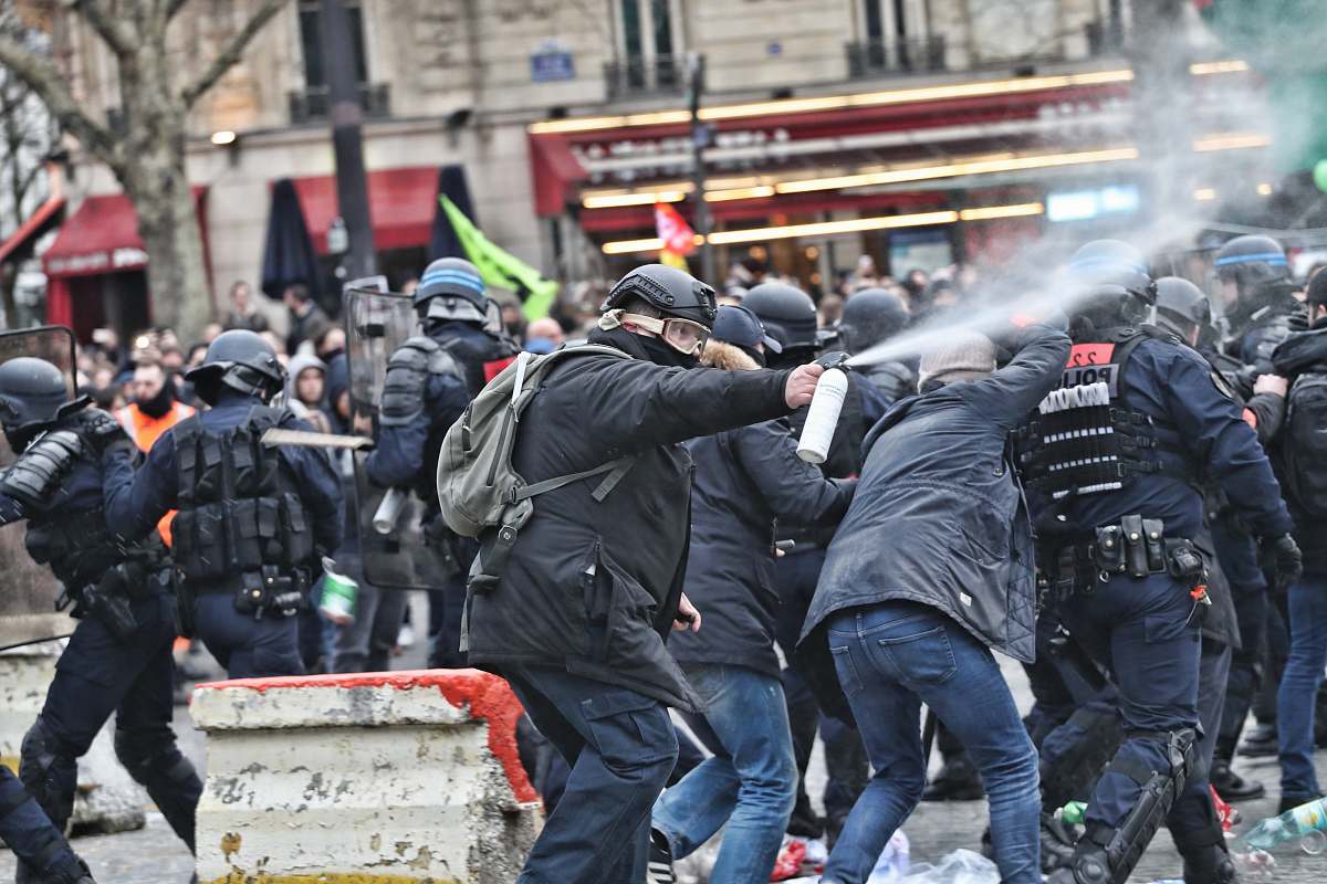 human riot police spraying unto protesters person
