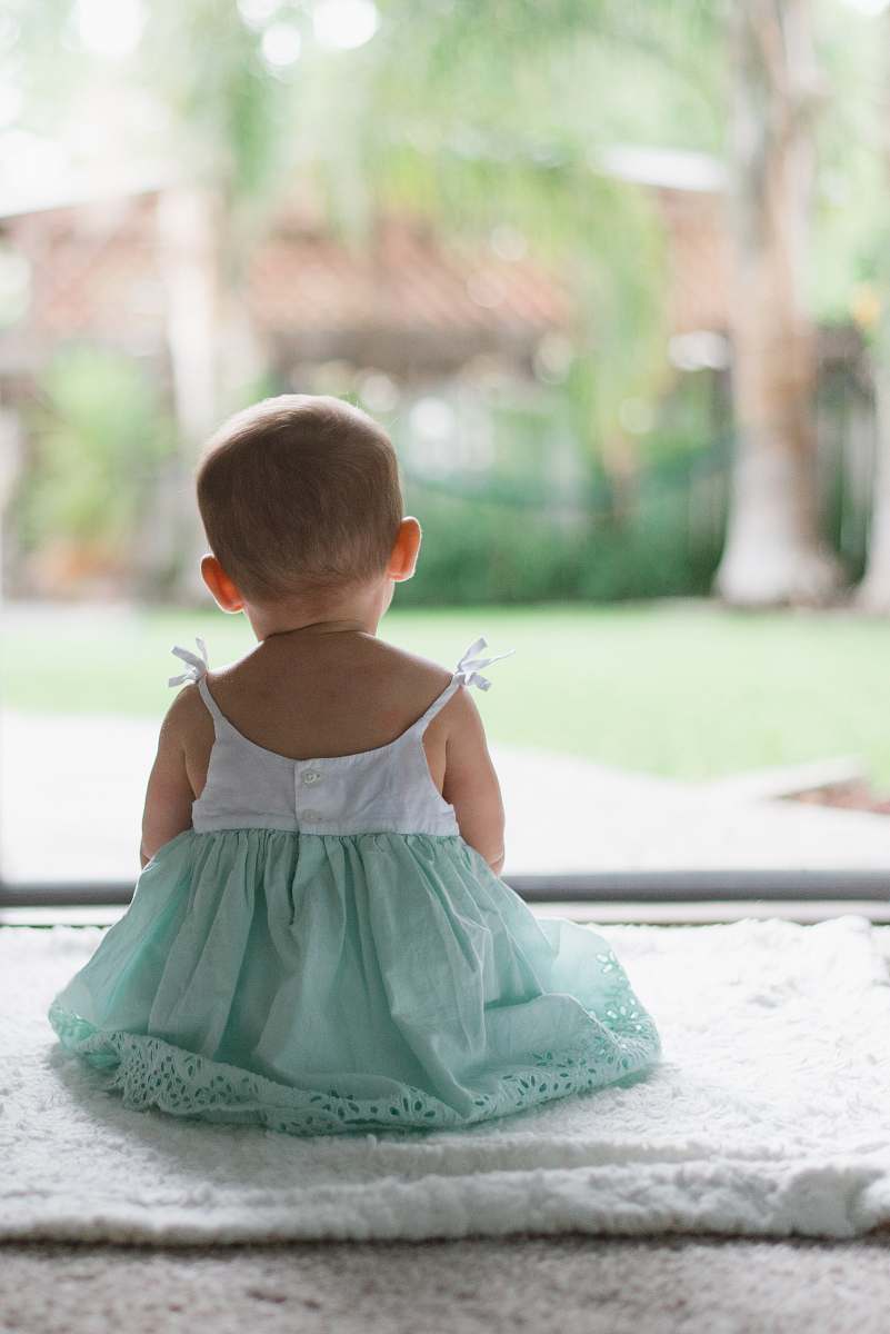 human selective focus photo of toddler wearing sleeveless dress sitting on floor baby