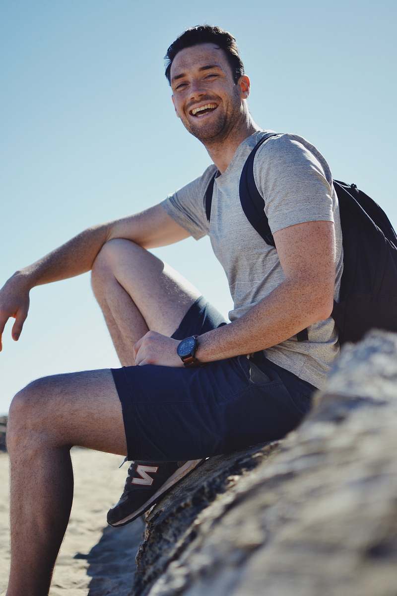 human smiling man sitting on gray rock at daytime person