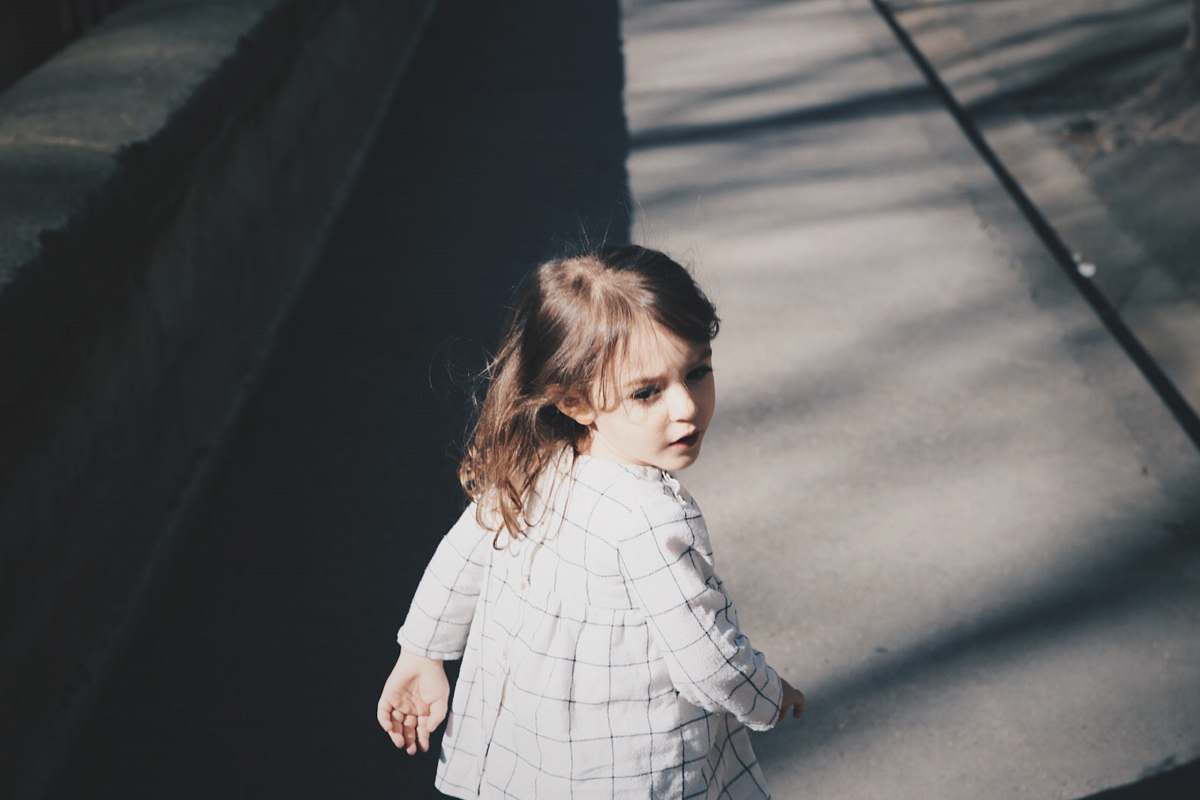 person toddler girl walking on gray concrete road at daytime human