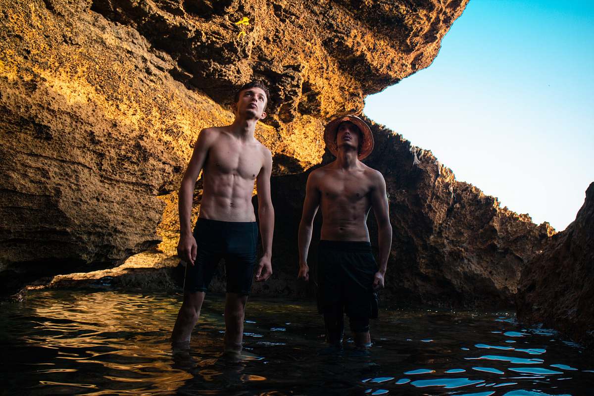 human two men standing near brown rock formation person